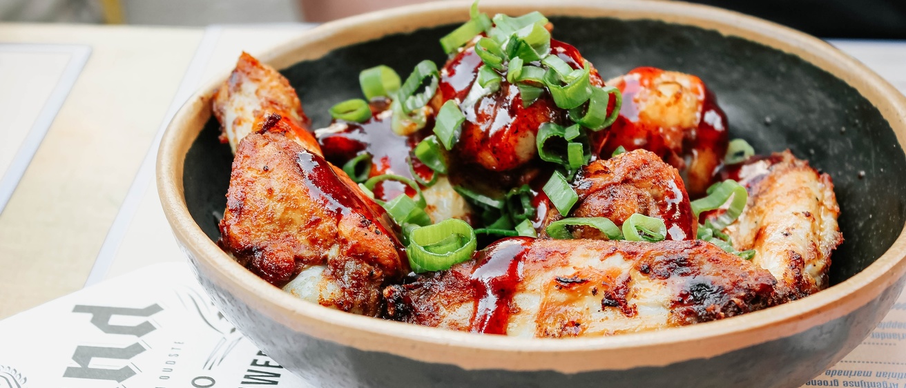 chicken drumsticks in sauce with green onions in bowl