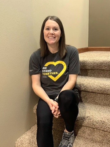 Dark haired woman sitting on carpeted stairs in gray t-shirt.