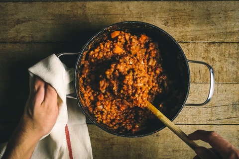 hand holding pot of stew being stirred