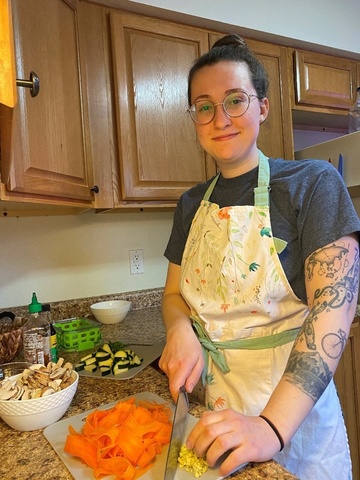 Laura Mantovani wearing apron in kitchen cutting carrots and other vegetables