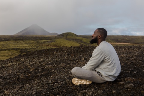 side view of man sitting crossed legged on dark ground