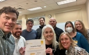 Groups of Ui staff council surround woman with grey hair holding certificate