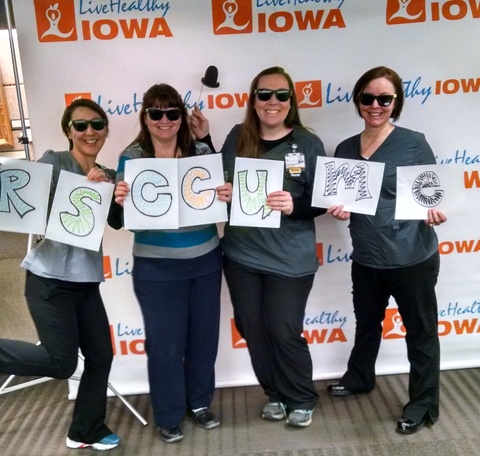 Group of happy women in scrubs (ER nurses) and sunglasses stand together holding sign of the name of their LHI group: "Rescue Me"