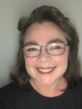 Headshot of smiling brunette woman with glasses