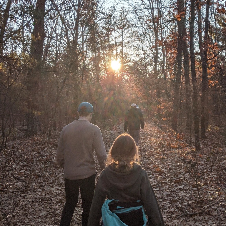 Photo of a family walking on a wooded trail covered with leafs