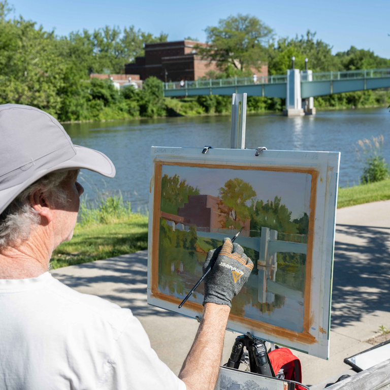 man painting a picture of the art building on University of Iowa campus.