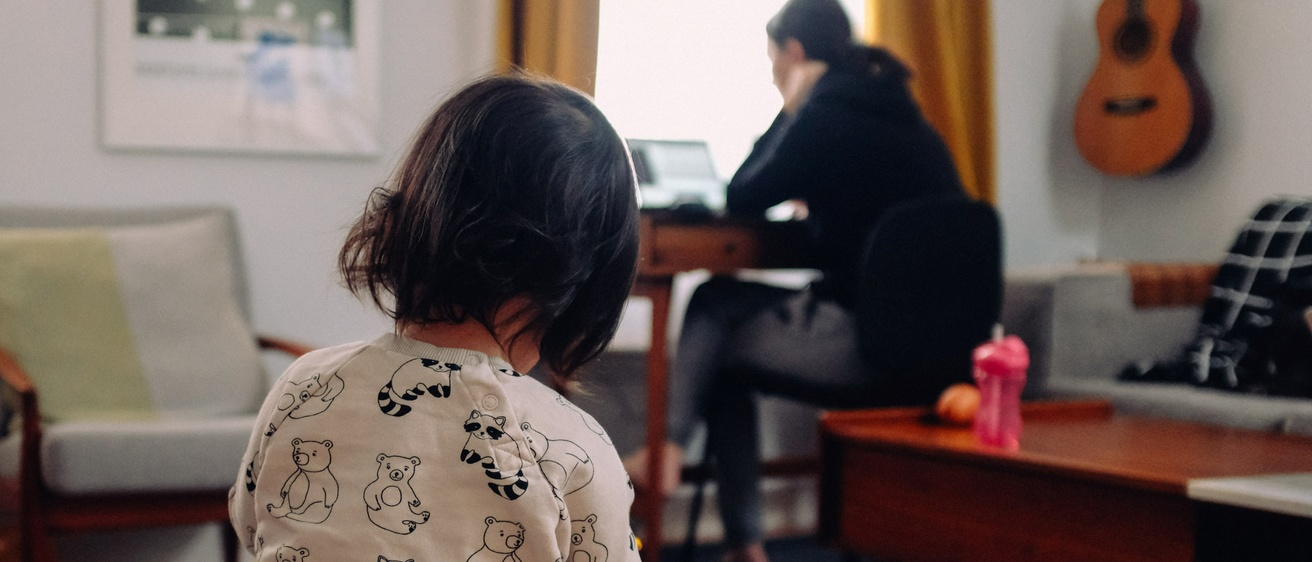 Woman working from home with small child in the foreground.