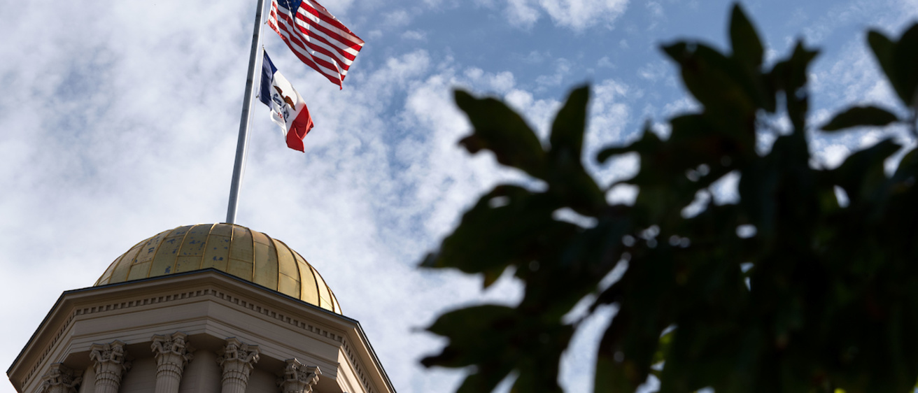 Flags flying at the top of the Old Capitol building on a partly cloudy day