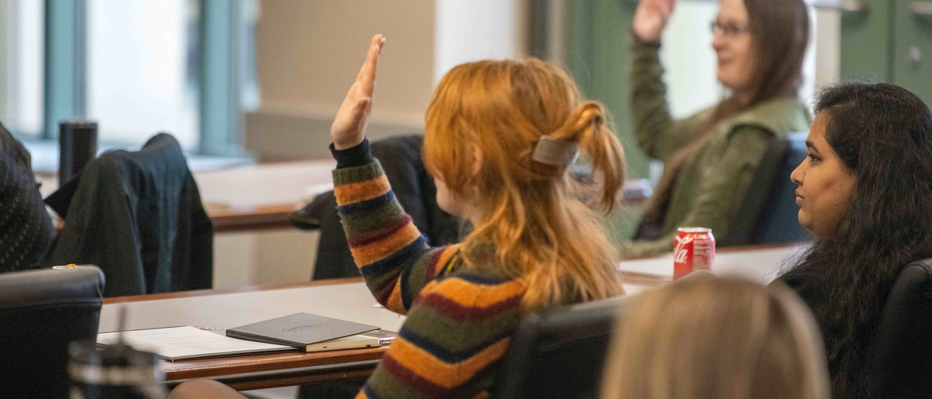 students raising their hands in a classroom