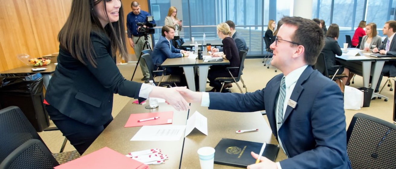 Individuals shake hands as part of a mock-interview process.
