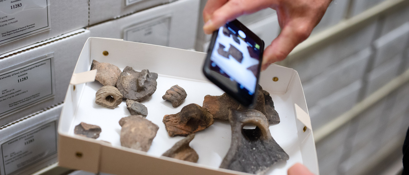 A professor photographs artifacts at the Office of the State Archeologist