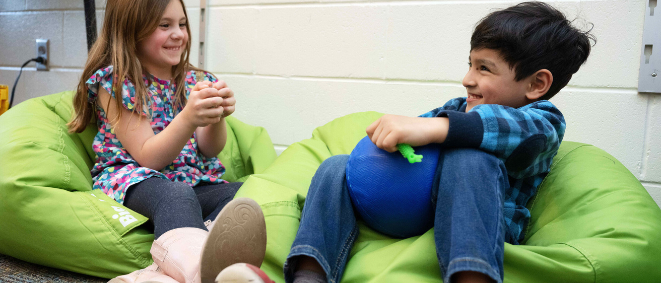 Children sitting on green bean bag chairs