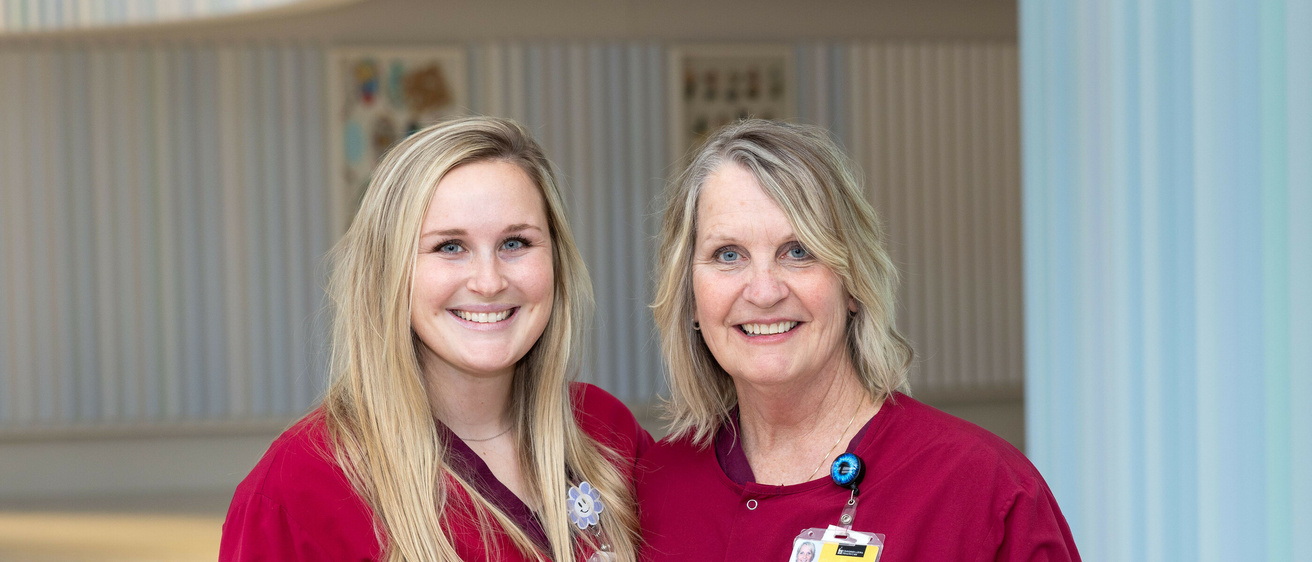 Jeanie Finnegan and Ashley Finnegan pose for a photo together wearing red scrubs
