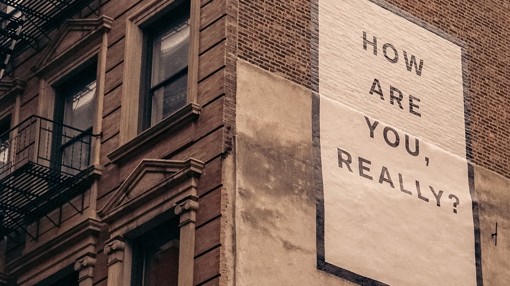 Corner of older brick building with sign reading, "How are you, really?"
