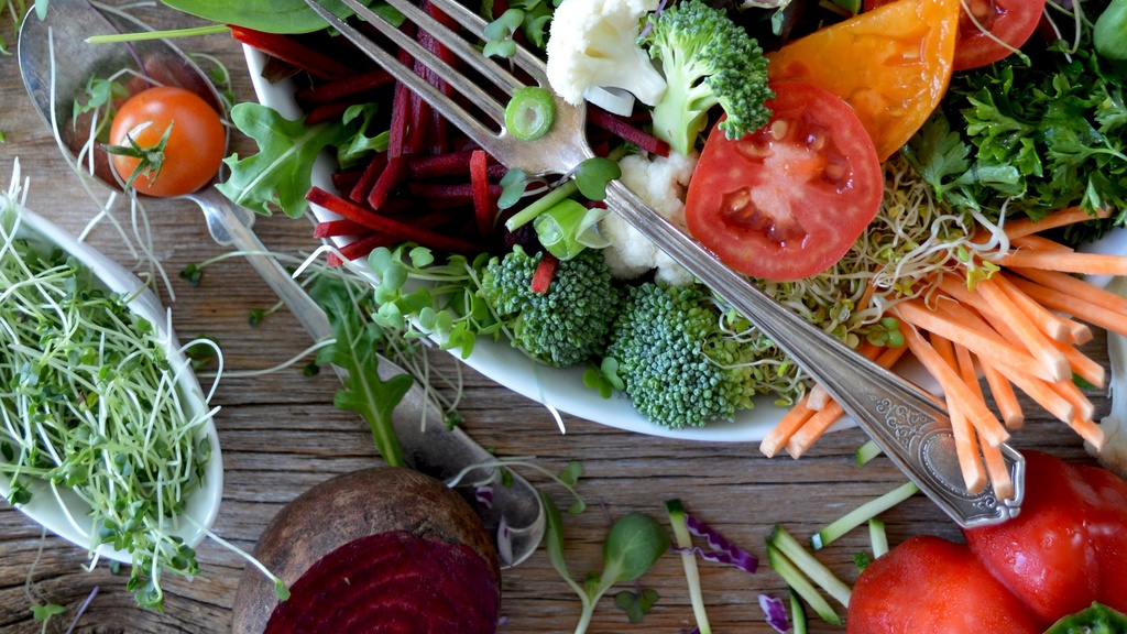 silver fork resting on overflowing salad bowl of colorful veggies and greens