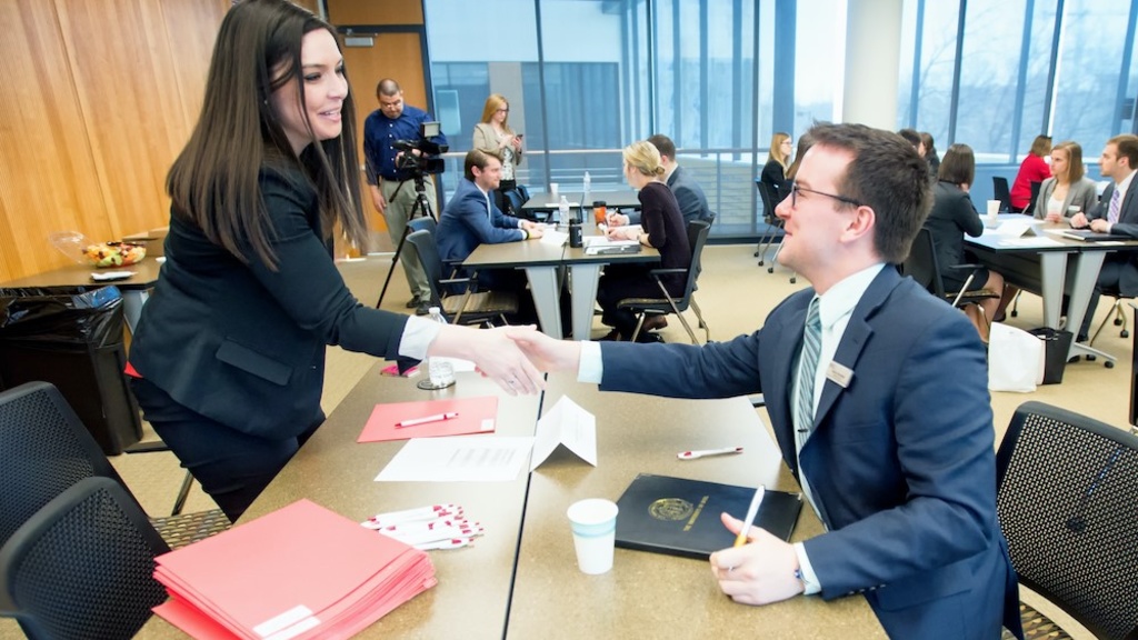 Individuals shake hands as part of a mock-interview process.