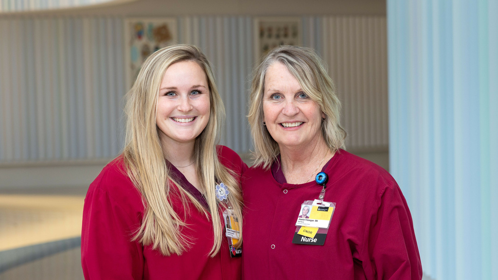 Jeanie Finnegan and Ashley Finnegan pose for a photo together wearing red scrubs