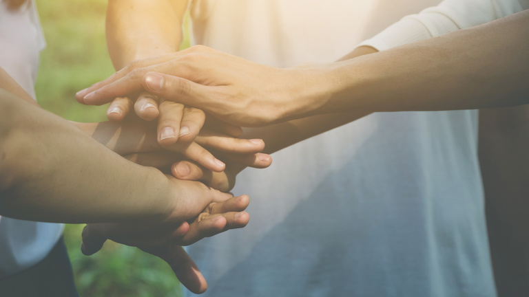 People stacking hands to show teamwork.