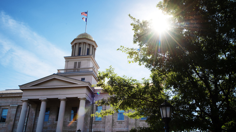 Low angle view of Old Capitol with sunlight flaring through adjacent tree